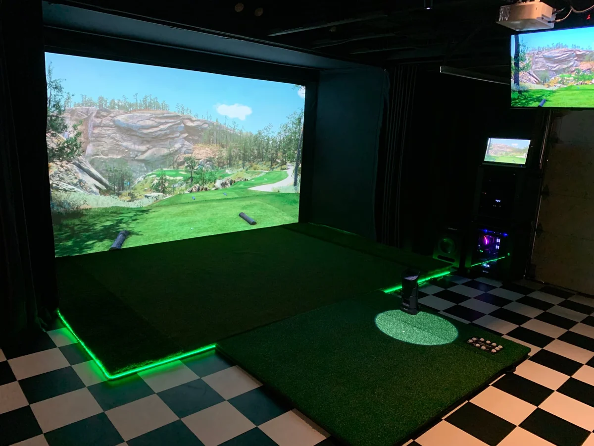 Indoor golf simulator room with screen and projector
