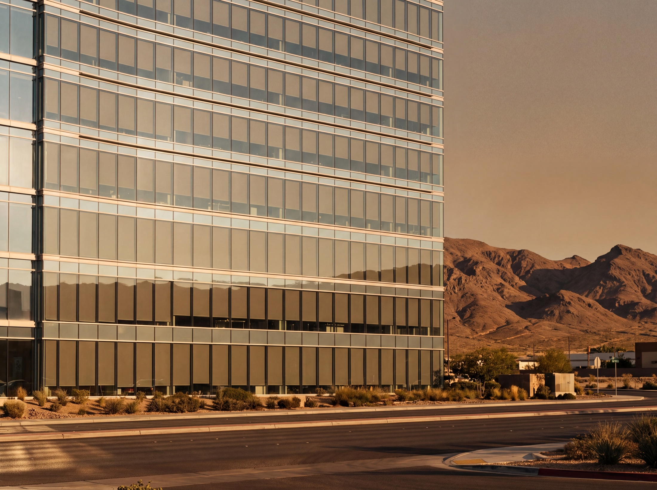 A Las Vegas office facade from the street, every window's shade at the same height, uniform bands across the elevation