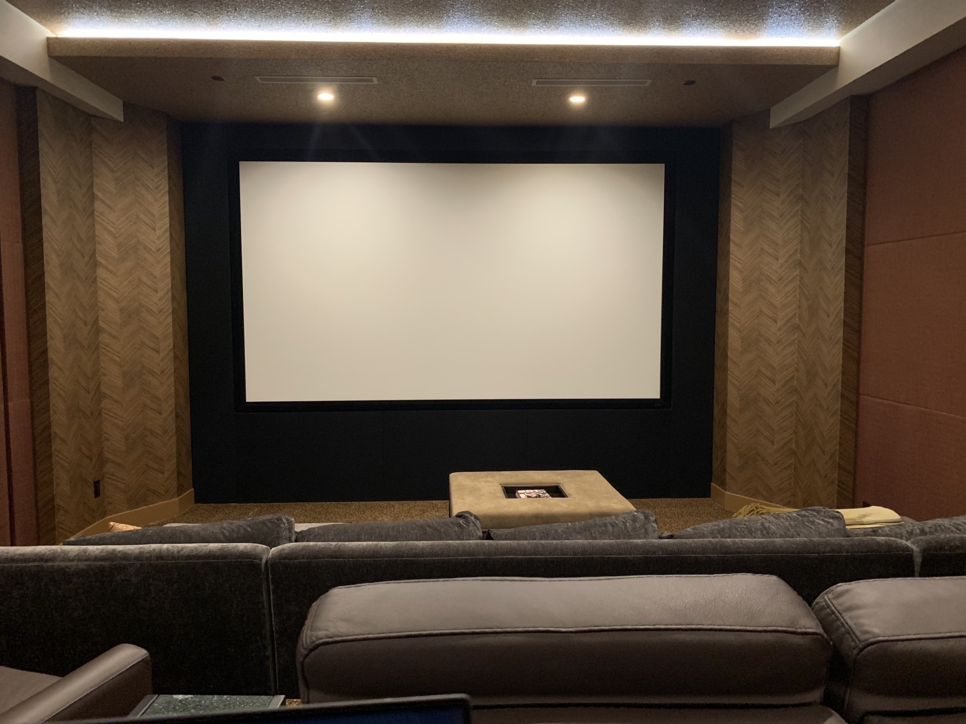 Finished home theater with herringbone acoustic panels and cove lighting