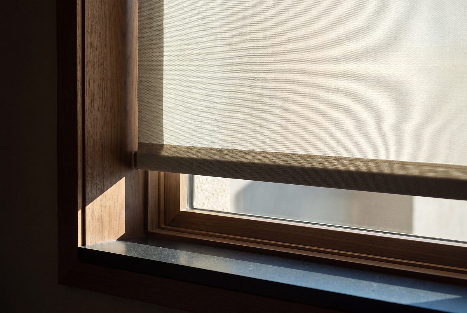 A motorized shade mid-travel against desert glare, hem perfectly level