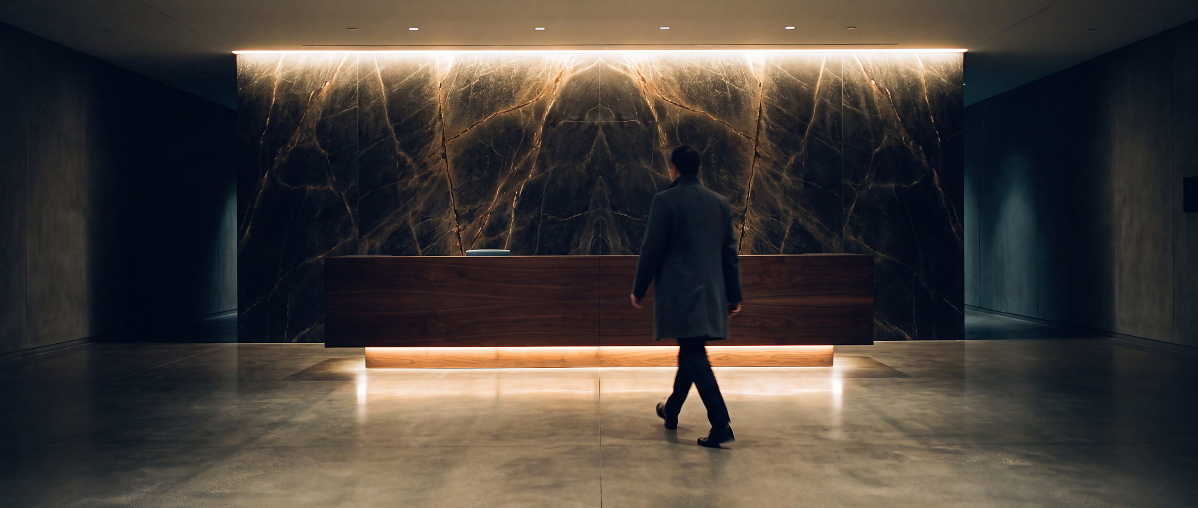 A commercial reception at night, lit stone feature wall, a person crossing the floor