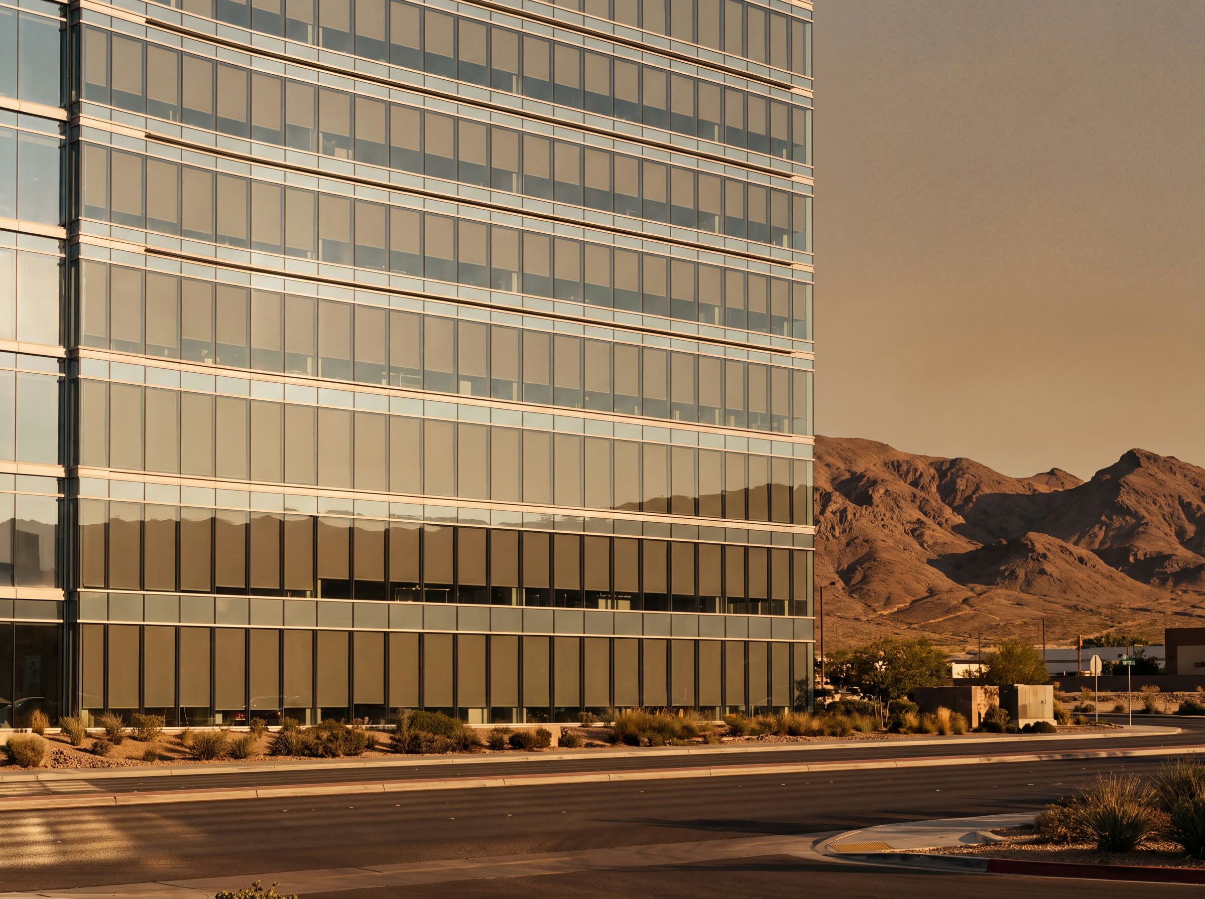 A Las Vegas tower at golden hour, interior shades level on every floor of the glazing