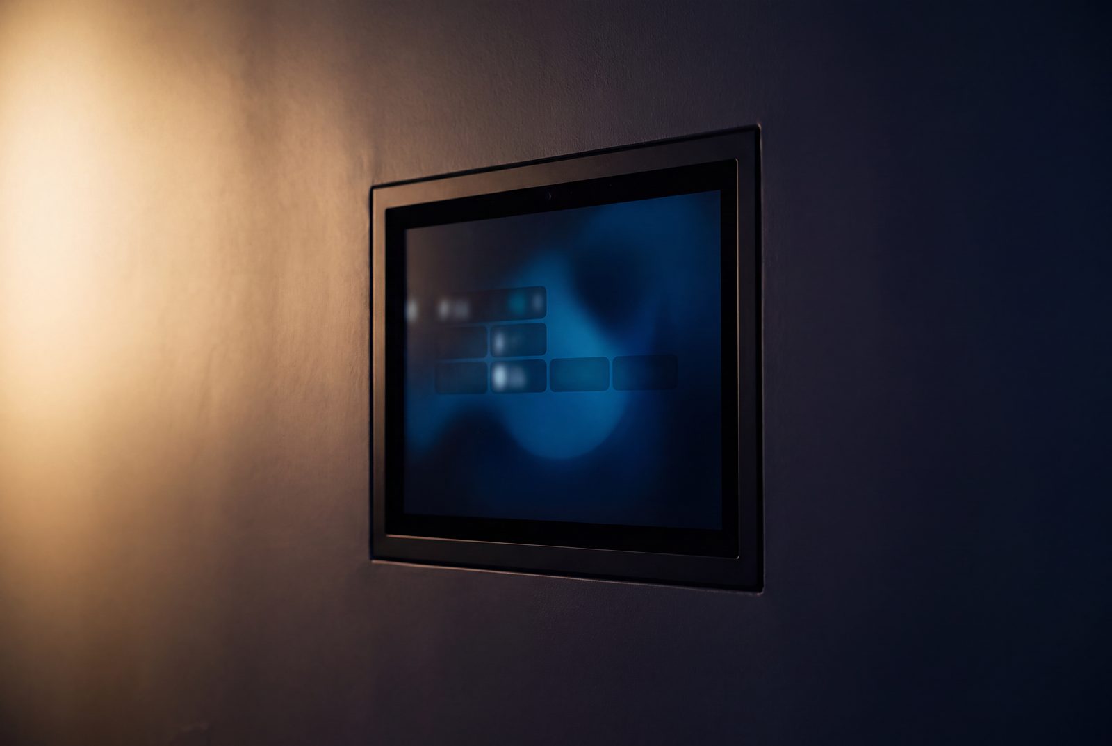 A Control4 T5 touchscreen flush in a dark plaster wall