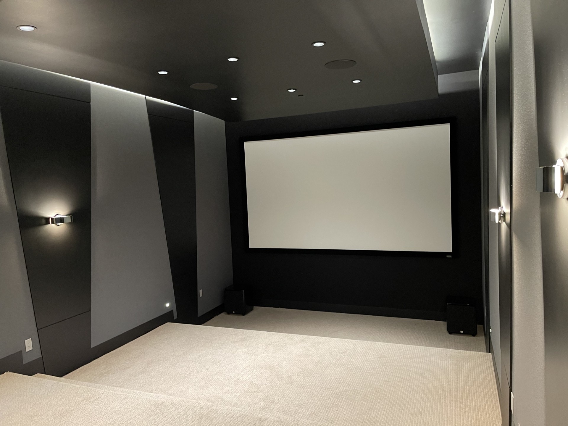 Theater mid-fitout: angular acoustic wall geometry and sconces before seating arrives