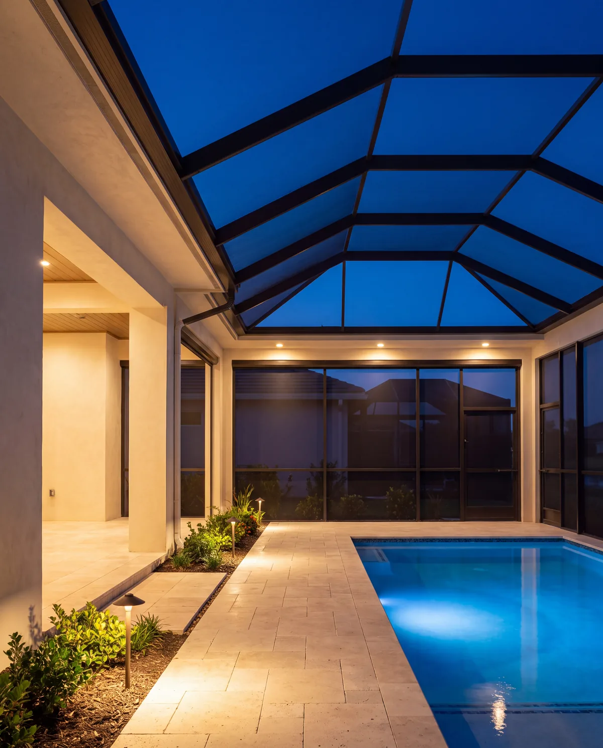 Screened pool lanai, step lights and downlights at dusk.