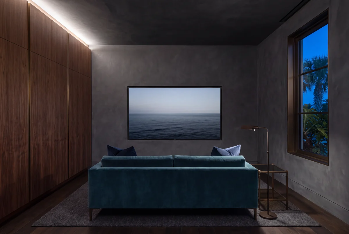 A media snug in charcoal, walnut and teal, a display set into the wall and lamps lit low