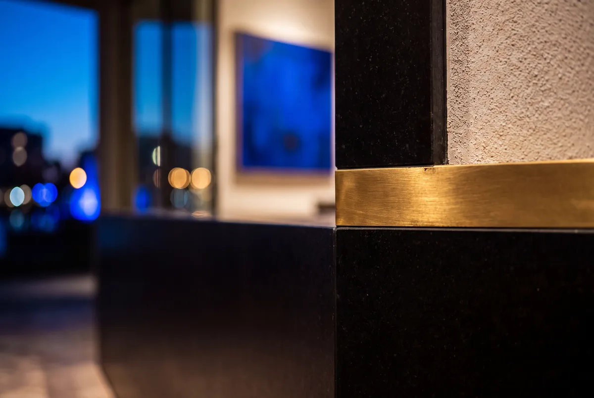 Plaster, stone and a brass edge, lit along the wall.