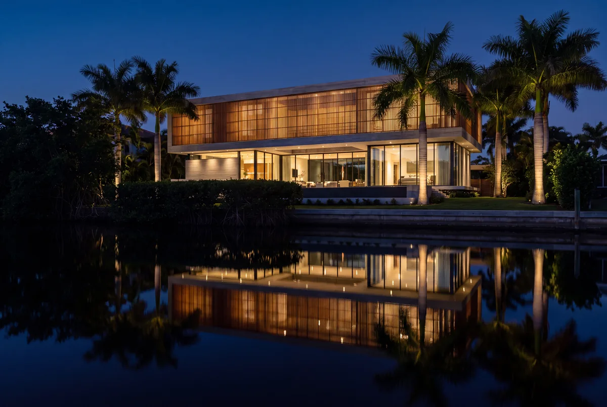 Waterfront house at dusk, interior light reflected across the water.