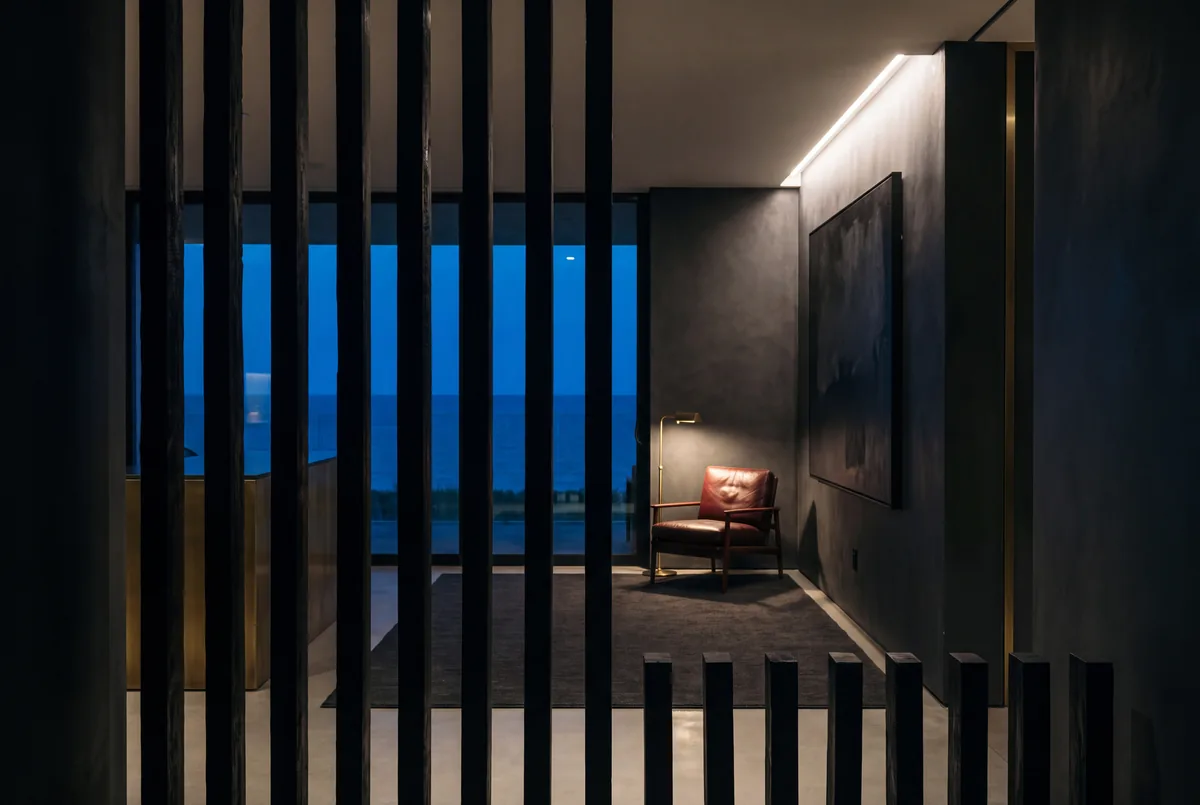 Dark entry through a slatted screen, cove light held low.