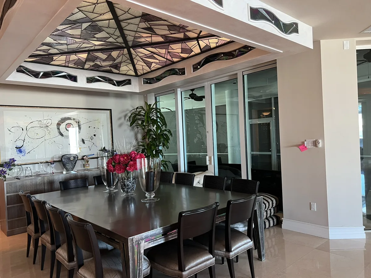 Dining room under a sculptural ceiling, lit to a low evening level.