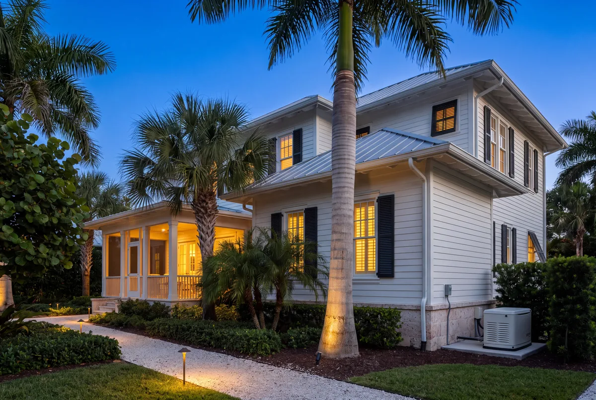 West Indies house at dusk, porch and path lights on.
